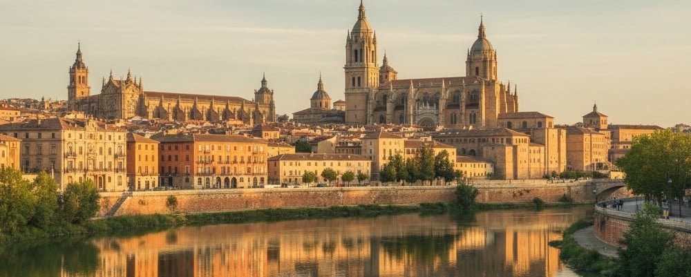 traduccion-jurada-salamanca Catedral Nueva de Salamanca y Puente Romano reflejados en el río Tormes al atardecer